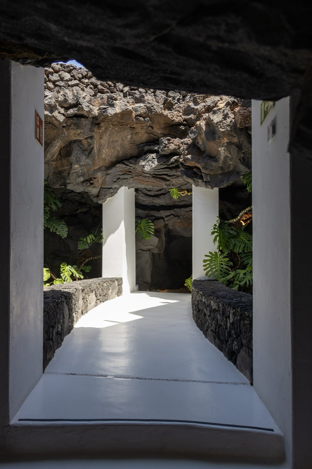 Pasillo blanco de la casa de César Manrique en Taro de Tahíche, que se abre a una burbuja de lava con helechos.