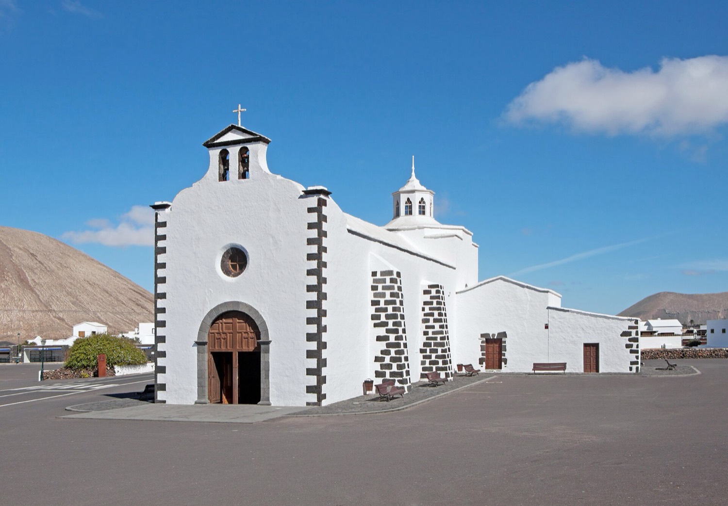 La ermita blanca de Nuestra Señora de Los Dolores en Mancha Blanca, con esquinas de piedra volcánica, bajo un cielo azul: el lugar que acoge cada septiembre la Feria Insular de Artesanía.