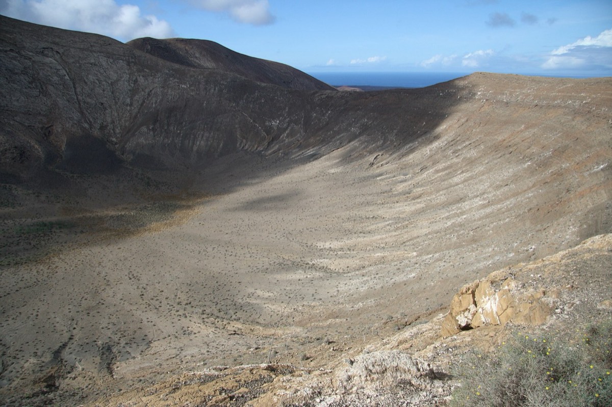 Interior del cráter de Caldera Blanca visto desde el borde, con el mar al fondo