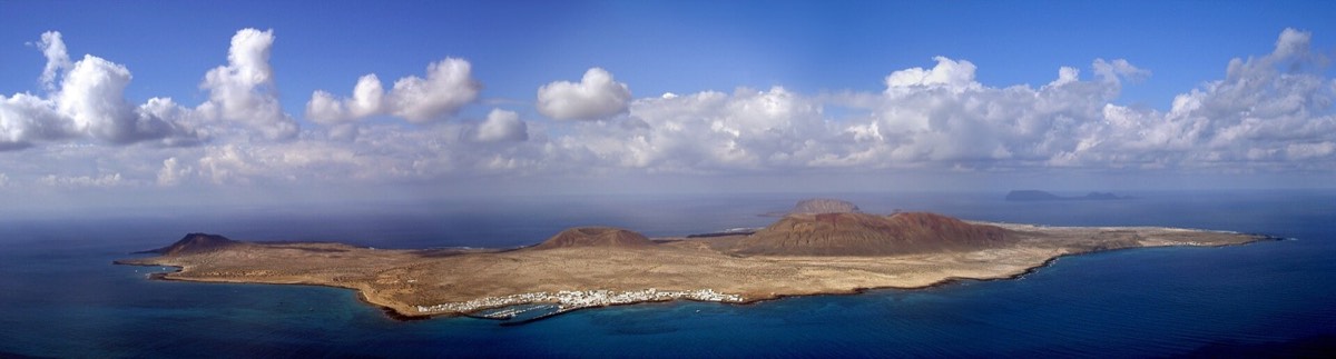 Panorámica de La Graciosa entera desde lo alto, con Caleta de Sebo junto al mar y sus volcanes