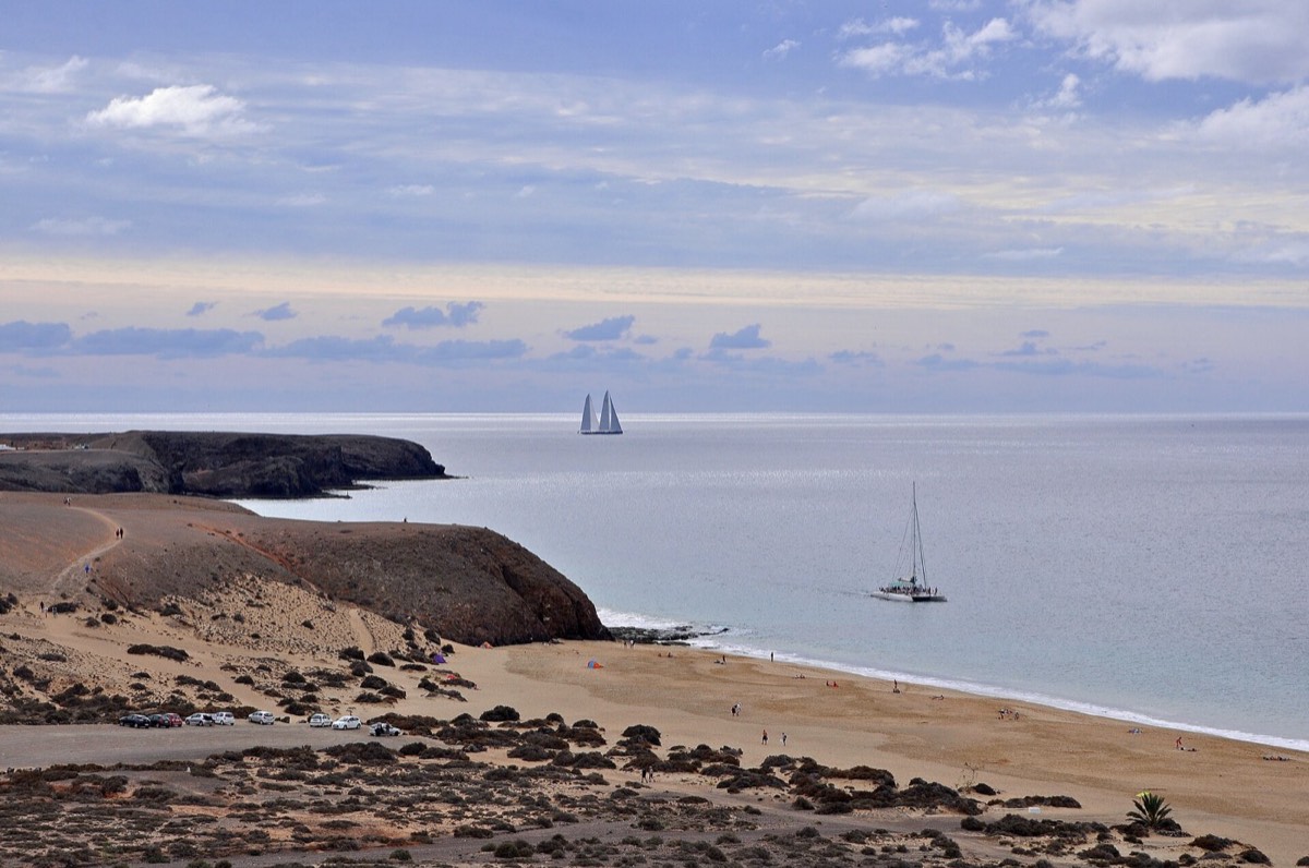 Playa de Papagayo entre promontorios, con veleros en el mar