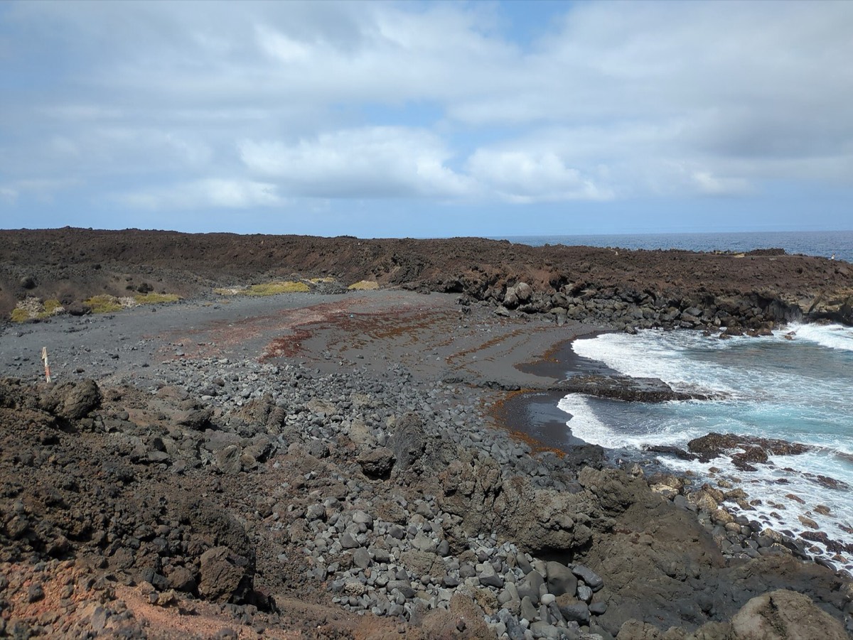 Playa de la Madera, cala de callaos y arena oscura entre coladas en la costa de Timanfaya