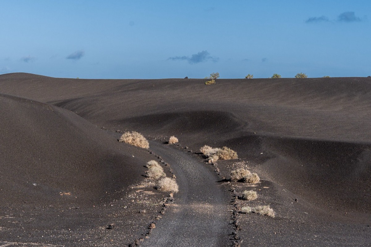 Sendero de Tremesana entre lomas de ceniza negra en el Parque Nacional de Timanfaya